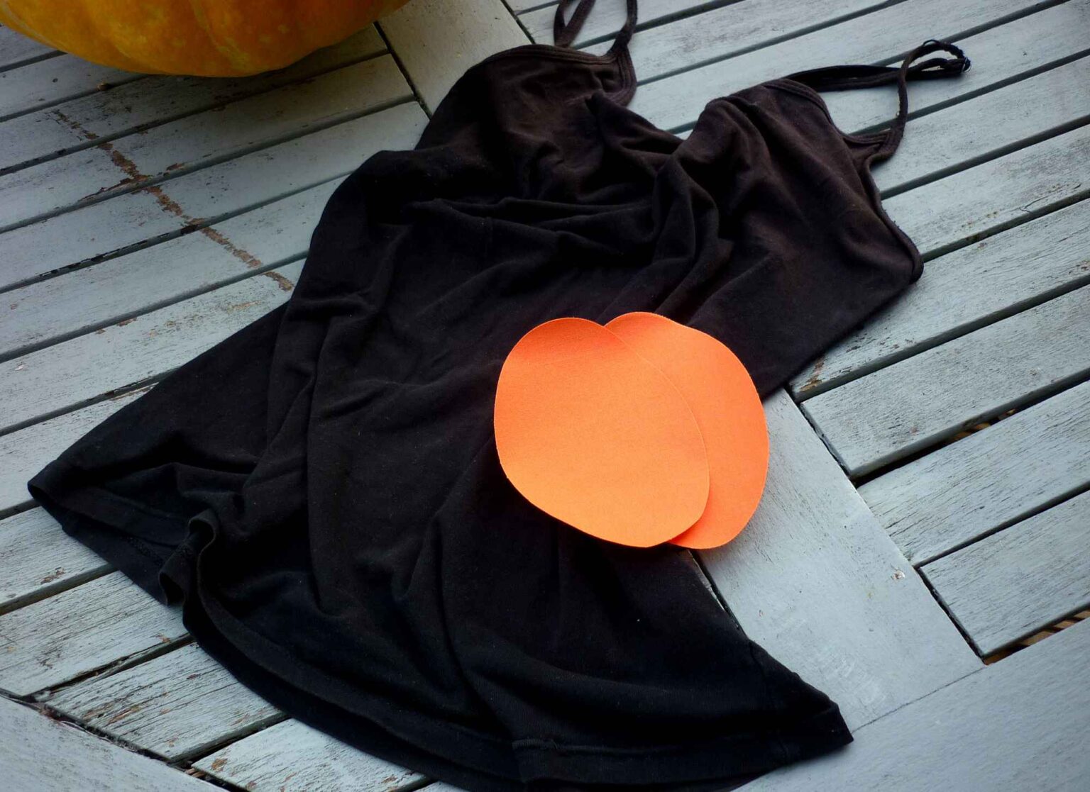 black strappy camisole vest top laid on table with two orange oval iron on patches