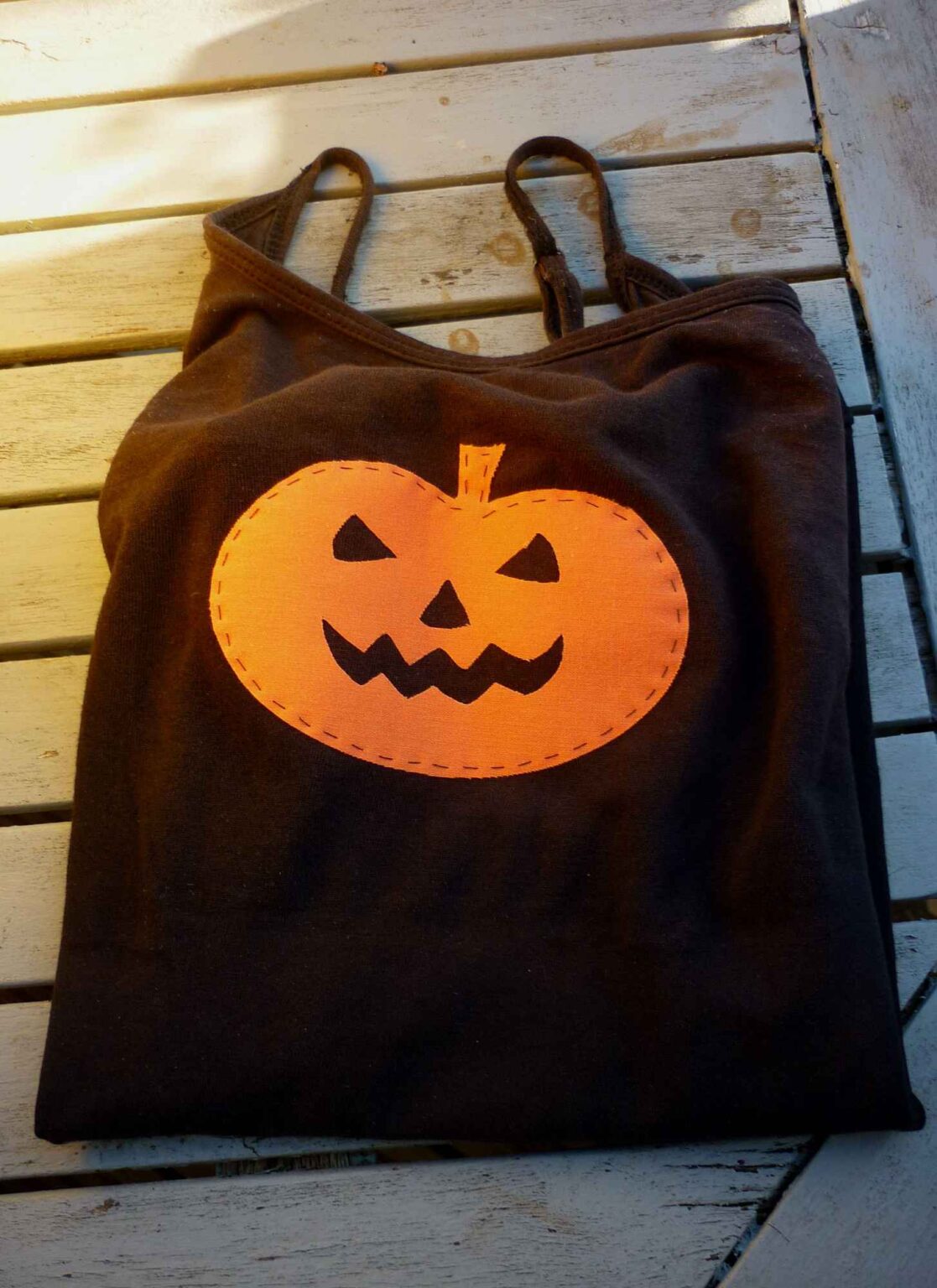 Black vest with orange pumpkin face motif folded on table