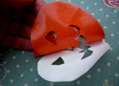 orange iron on pumpkin face motif with backing paper partially peeled off